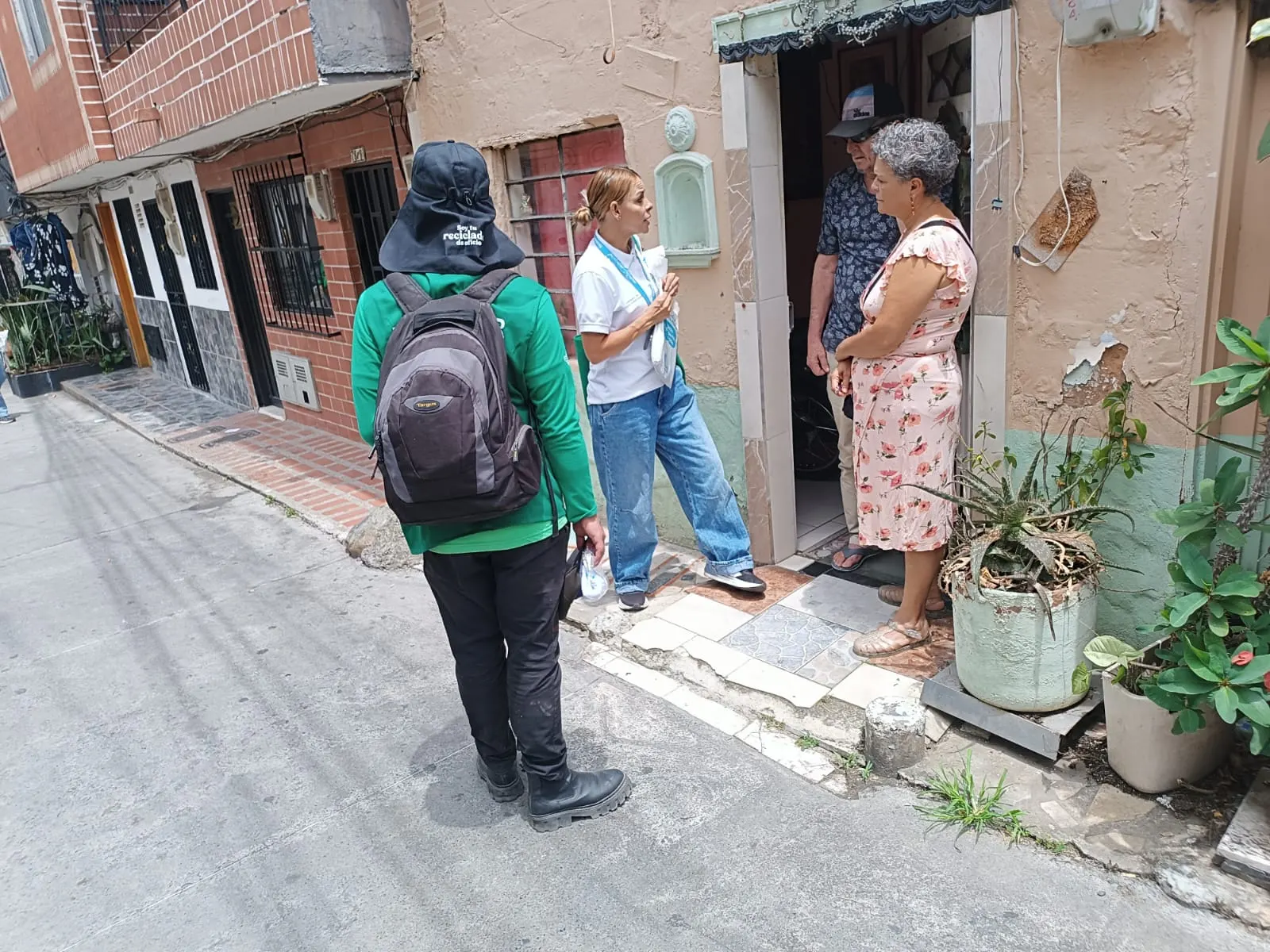 Equipo de CORASEARES conversando con vecinos en la puerta de una casa durante la recolección